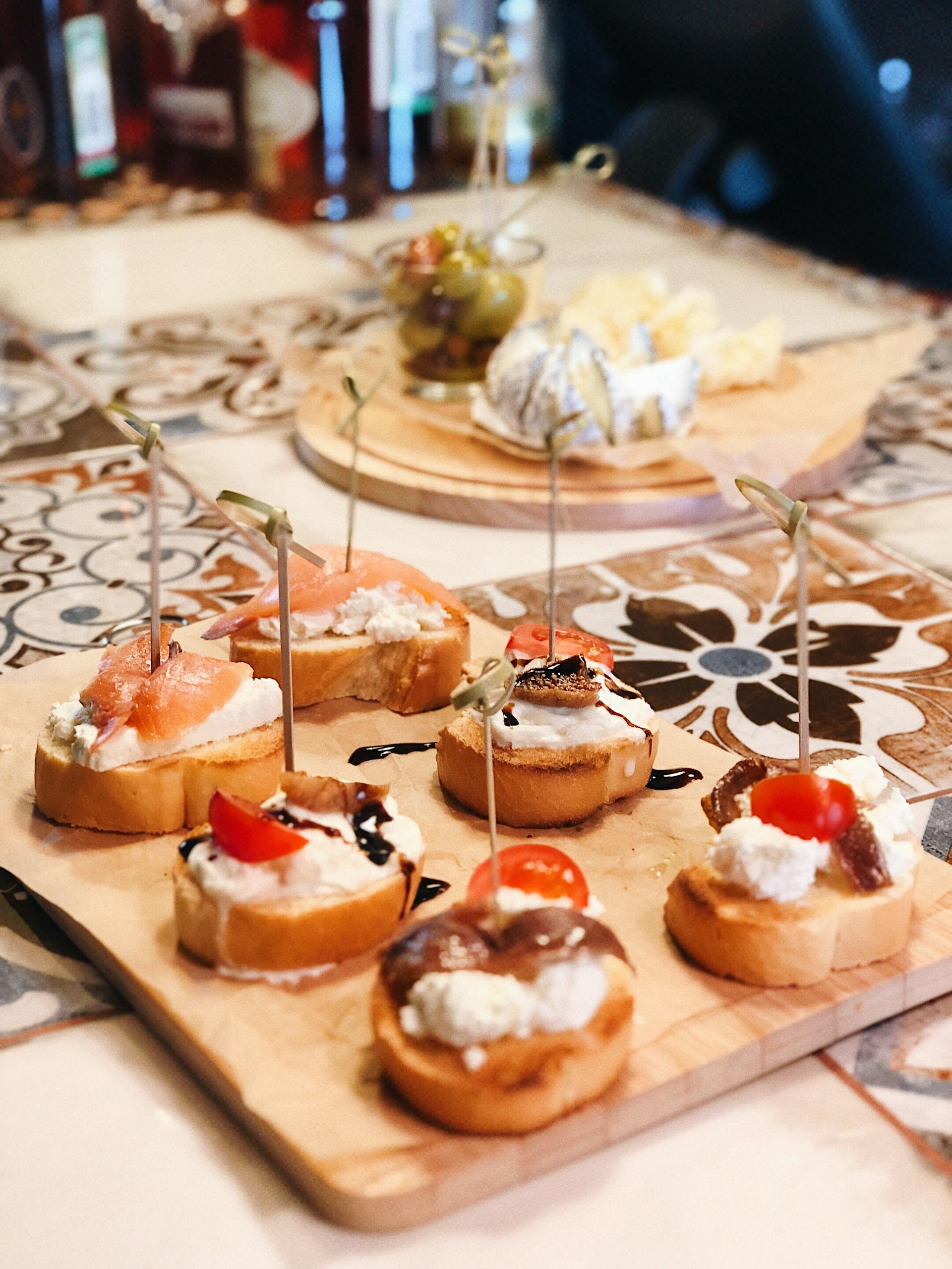 Delicious assortment of gourmet tapas with cheese, salmon, and cherry tomatoes on a decorative board.